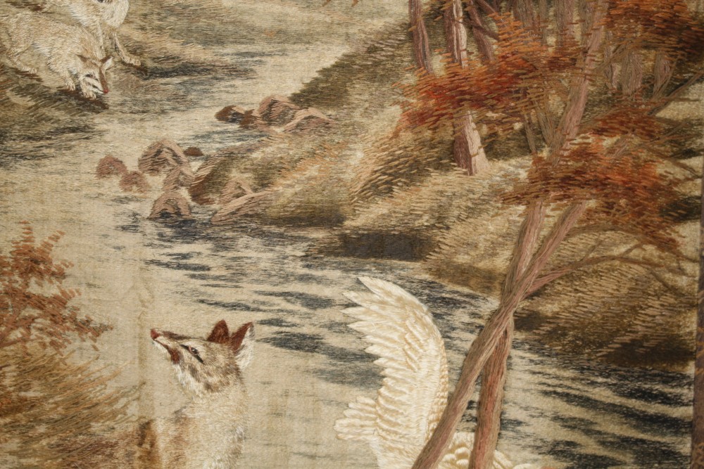 A 20th century Japanese silk panel, depicting wolves hunting geese beside a woodland stream, the inner panel 173 x 115cm, overall 205 x